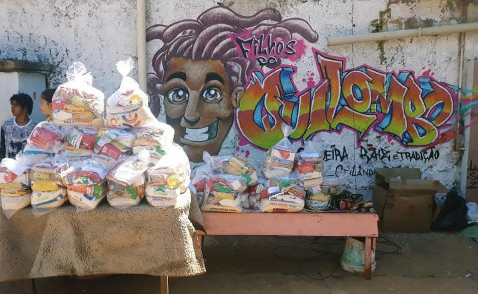 Mural de grafite colorido com o nome Filhos do Quilombo nas paredes externas do Ponto de Cultura, com cestas básicas de alimentos no local